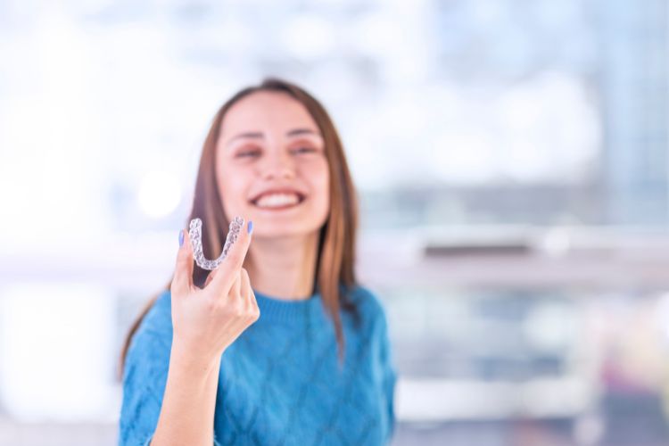 mujer con alineadores dentales en la mano